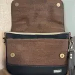 sac femme en liège noir profond et liège marron. Sac ouvert sur détail fermeture du rabat et poche plaquée avant.