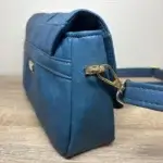 Sac à main femme en cuir écologique. Couleur bleu canard. Format pochette compacte. Porté bandoulière. Fixation de la bandoulière.