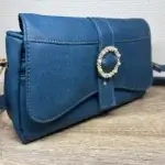 Sac à main femme en cuir écologique. Couleur bleu canard. Format pochette compacte. Porté bandoulière. Profil du sac.
