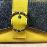 Sac à main femme en liège végétalien. Couleur jaune et empiècement noir motif grainé brillant Format pochette compacte. Porté bandoulière. Boucle décorative.