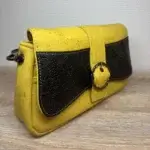 Sac à main femme en liège végétalien. Couleur jaune et empiècement noir motif grainé brillant Format pochette compacte. Porté bandoulière. Vue de profil.