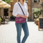 Sac à main femme en cuir écologique. Couleur vert. Format pochette compacte. Porté bandoulière. Empiècement effet peau de serpent. porté par mannequin IA.