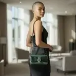 Sac à main femme en cuir écologique. Couleur vert.Forma pochette compacte. Porté bandoulière. Empiècement effet croco. porté par mannequin IA