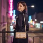 Sac à main femme en liège végétalien. Couleur beige et motifs géométriques. Format pochette compacte. Porté bandoulière par mannequin IA.