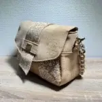 Sac à main de fabrication artisanale en liège végétal beige naturel et imprimé arabesque blanc. Modèle avec rabat et bandoulière réglable. Vue profil.