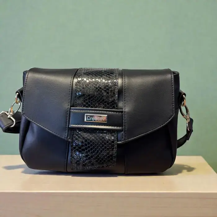 sac à main pour femme en cuir écologique haut de gamme noir. Vu avant sur le rabat et le détail de la sangle style cravate.