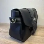 sac à main pour femme en cuir écologique haut de gamme noir. Profil avec attache bandoulière.