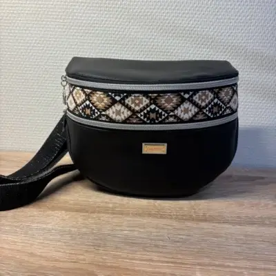Sac banane en cuir synthétique noir effet satiné. Trois poches zippées. Intérieure toile imperméable. Bandoulière réglable.