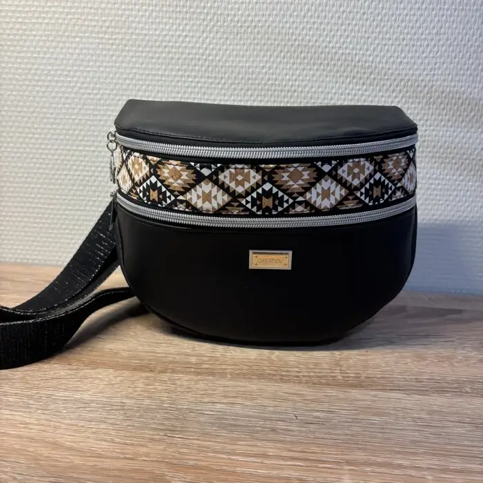 Sac banane en cuir synthétique noir effet satiné. Trois poches zippées. Intérieure toile imperméable. Bandoulière réglable.