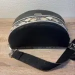Sac banane en cuir synthétique noir effet satiné. Trois poches zippées. Intérieure toile imperméable. Bandoulière réglable. Vue dessus.