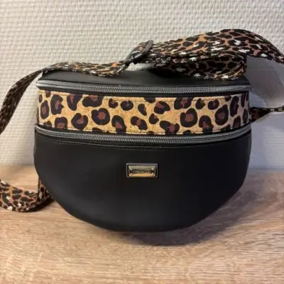Sac banane en cuir synthétique noir effet satiné motif léopard. Trois poches zippées. Intérieure toile imperméable. Bandoulière réglable.