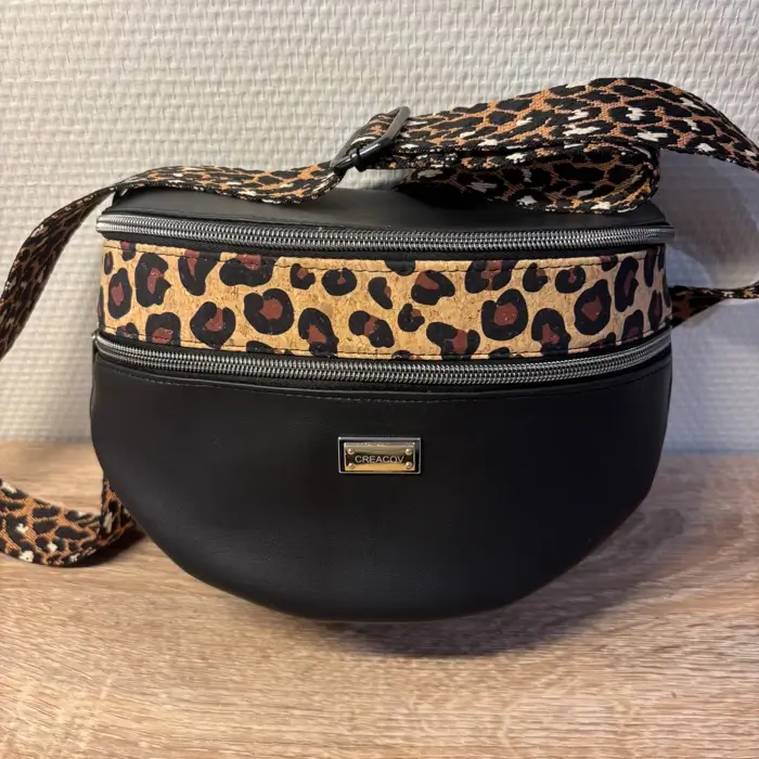 Sac banane en cuir synthétique noir effet satiné motif léopard. Trois poches zippées. Intérieure toile imperméable. Bandoulière réglable.