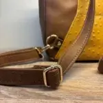 Sac à dos en cuir écologique marron clair et jaune piqué marron. Détails bretelles réglables.