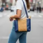 Sac à main style tote-bag, cuir écologique bleu marine et marron clair tressé. porté épaule par un mannequin IA.