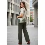 Sac à main de fabrication artisanale en cuir écologique vert et beige, empiècement effet mosaïque. interface structuré et géométrique. Portée par mannequin IA.